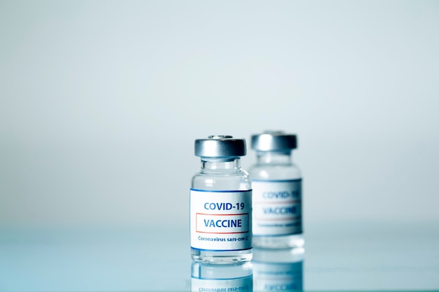 Vaccine against COVID-19. Glass medical vials with liquid. Ampoules with coronavirus vaccine on a medical glass table