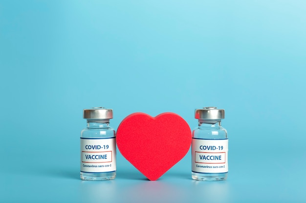 Vaccine against covid glass medical vials with liquid ampoule with coronavirus vaccine and heart on ...