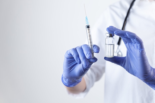 Vaccine bottle and syringe in doctor hands in rubber gloves