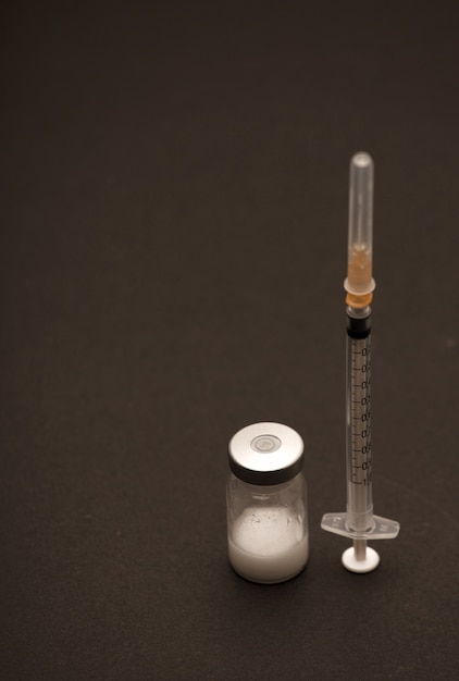 vaccine bottle with syringe, and black surface