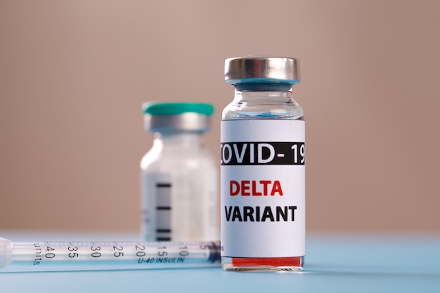 Бутылки с вакциной covid - дельта-вариант 19, лекарство во флаконах и шприц для инъекций, изолированные на синем. Коронавирус DELTA 2019-ncov.
