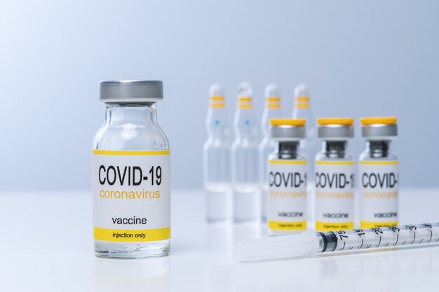 vaccine in glass vial with syringe on a table