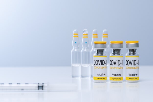 vaccine in glass vial with syringe on a table
