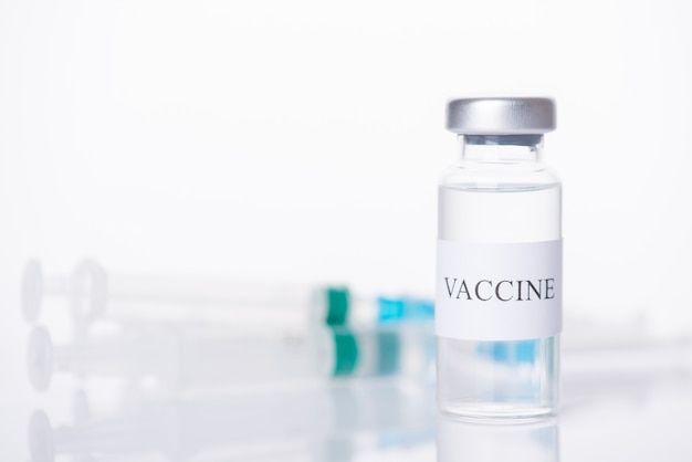 Vaccine treatment concept. Close-up photo of vaccine vial and blurred shot behind isolated on white background