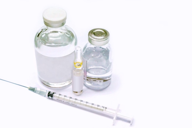 バイアル瓶にワクチンを入れ、白い背景に3mlのアンプルの薬剤とプラスチック注射器を入れます