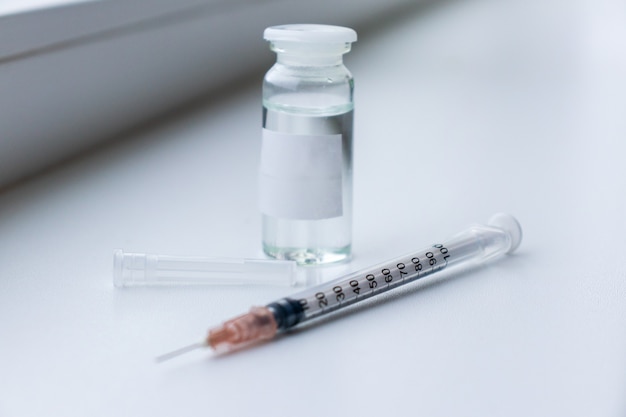 Vaccine on a vial bottle and injection Syringe on a white table
