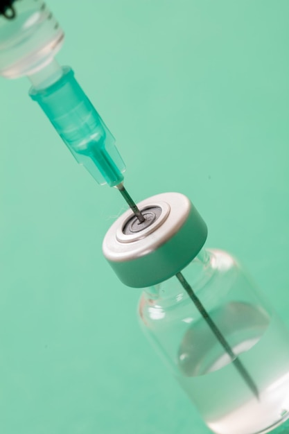 Доза флакона вакцины и шприц на зеленом фоне