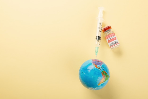 Vaccine vials bottles syringes for vaccination against coronavirus and globe