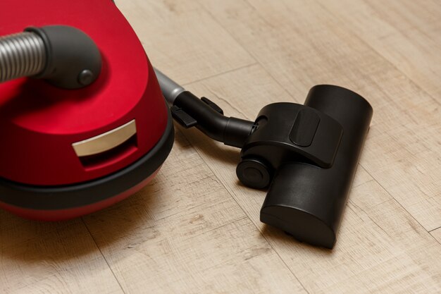 Vacuum cleaner on floor, cleaning service, new red vacuum cleaner.