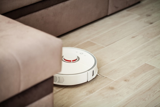 Vacuum cleaner robot runs on wood floor in a living room,