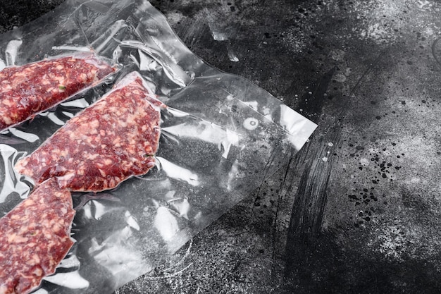 Vacuum packed cutlet or patty set, on black dark stone table background, top view flat lay, with copy space for text