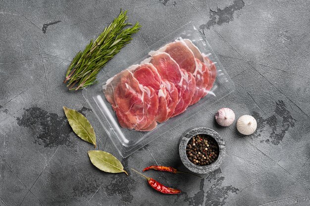 Vacuum packed serrano ham set, on gray stone table background, top view flat lay