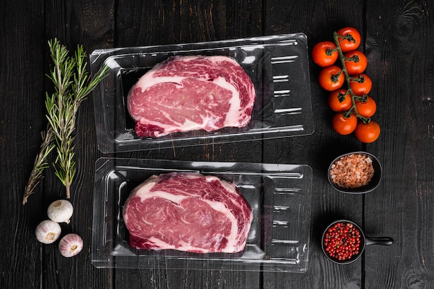 Vacuum sealed meat cut set, on black wooden table background, top view flat lay