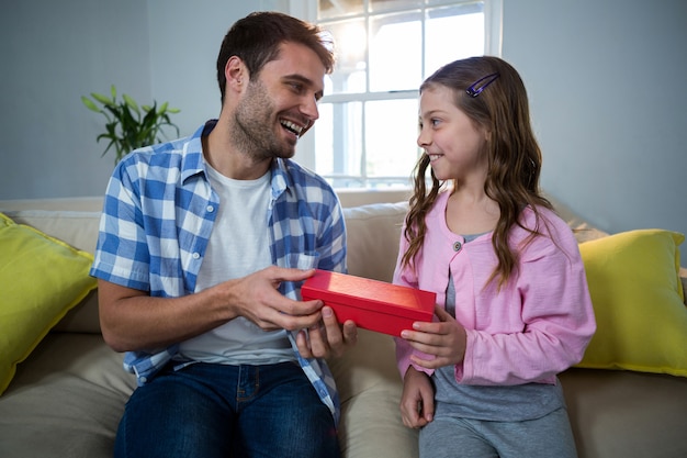 Vader die gift geeft aan dochter in de woonkamer