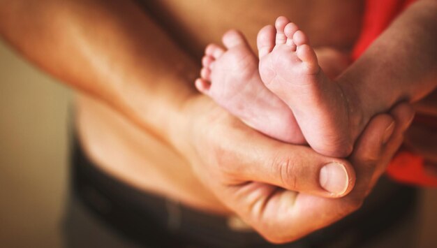 Vader die pasgeboren babyvoeten op zijn handen houdt