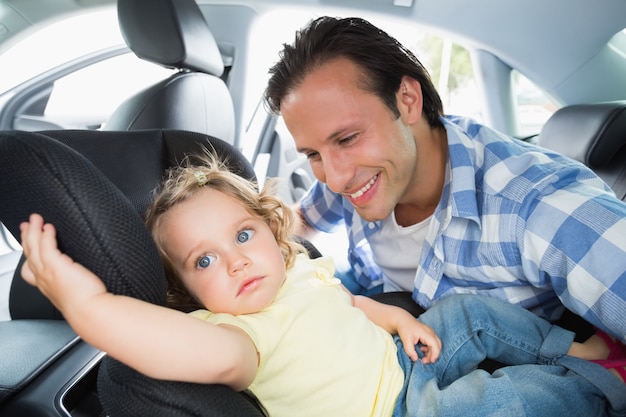 Vader die zijn baby in de autozetel beveiligt