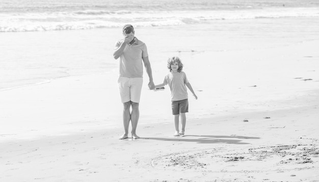 Vader die zijn ogen bedekt en zoon lopen op zomervakantie op het strand