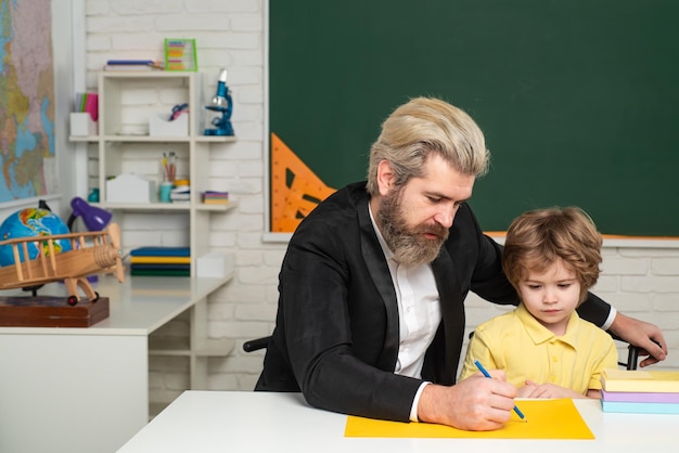 Vader die zoon schattige kleine voorschoolse jongen met leraar studeert in een klas privé kind tu