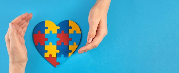 Vader en autistische zoon houden elkaar vast met een puzzel in de vorm van een hart Wereld Autisme Awareness Day