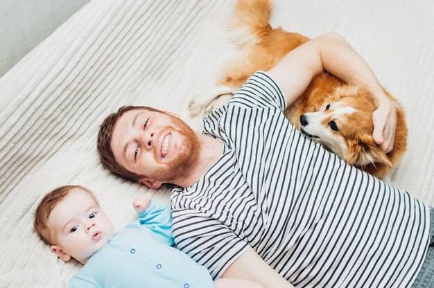 Vader en baby liggend op het bed met een hond