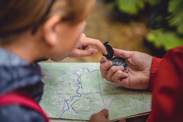 Vader en dochter die in bos wandelen en kaart controleren