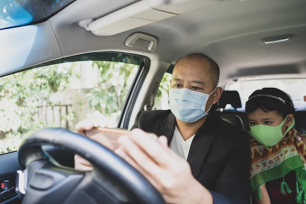 Vader en dochter dragen beschermend gezichtsmasker terwijl ze in de auto naar smartphone kijken