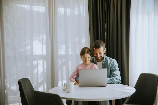 Vader en dochter gebruiken laptop samen in de kamer