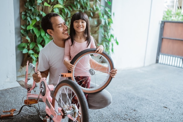 Vader en dochter glimlachen terwijl ze een wiel dragen