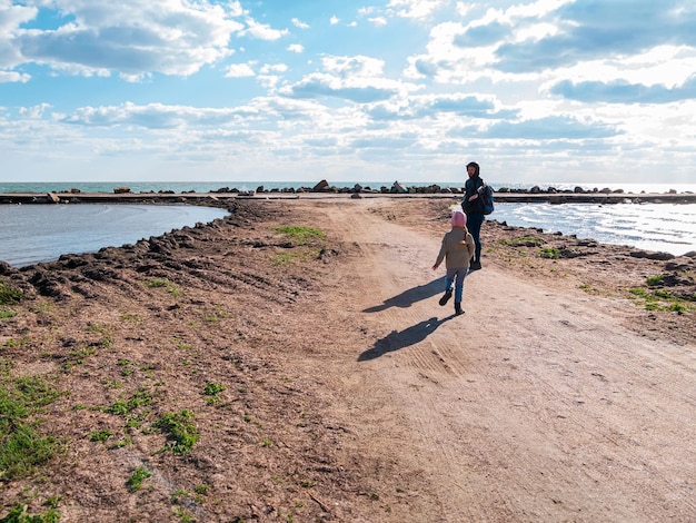 Vader en dochter glimlachen wandelen rennen op leeg strand Lifestyle foto echte mensen Gelukkige actieve familie die plezier heeft