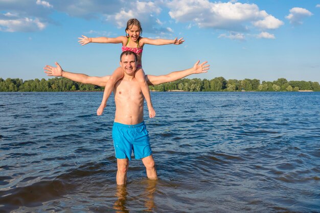 Vader en dochter hebben plezier in het water en poseren voor de camera. Familie spellen.