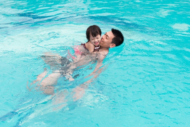 Vader en dochter hebben plezier in het zwembad. Zomervakantie en vakantieconcept