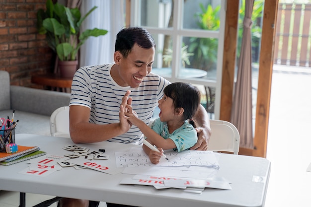 Vader en dochter high five terwijl thuis samen studeren