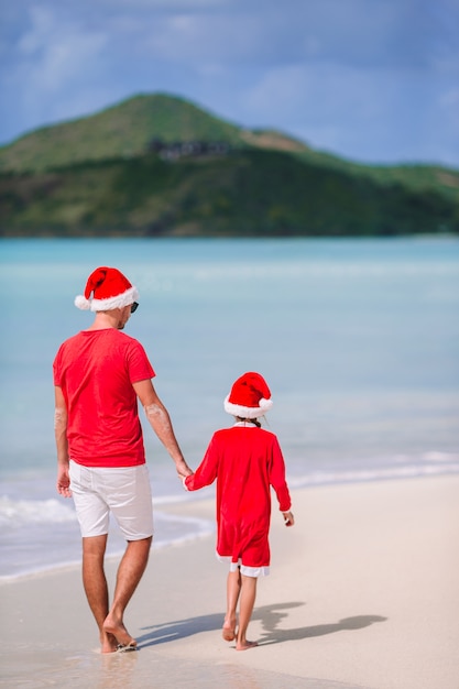 Vader en dochter in Santa Hat hebben plezier op tropisch strand