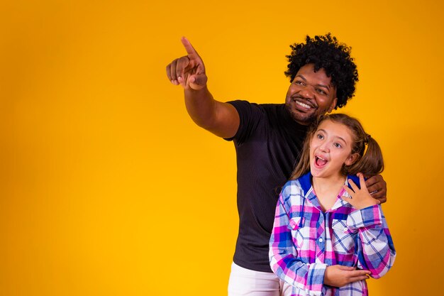 Vader en dochter op gele achtergrond met ruimte voor tekst Vader wijst naar de horizon en toont iets aan zijn dochter