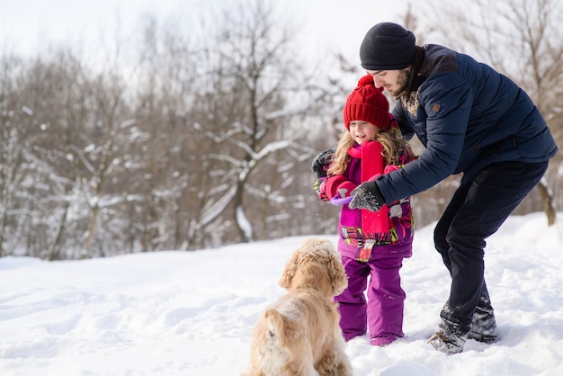 Vader en dochter trainen hun hond tijdens de winterwandeling