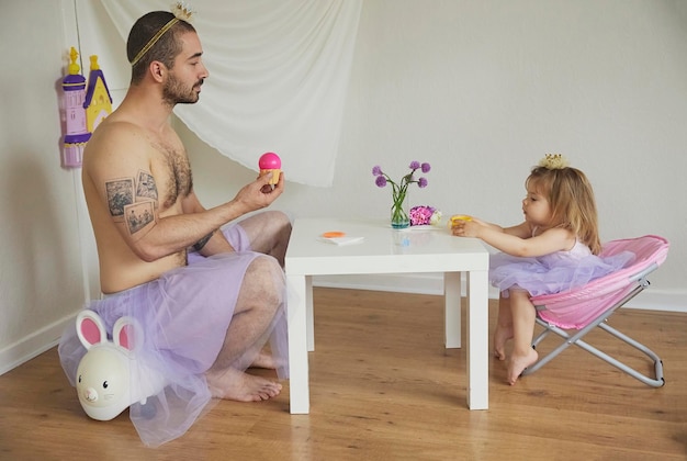 Vader en dochter verkleed als prinsessen lunchen aan de speelgoedtafel