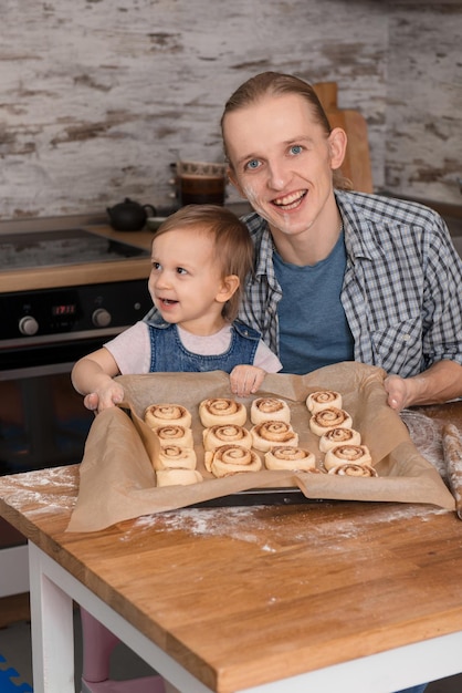 Vader en kind bakken Cinnabons op de keuken met plezier
