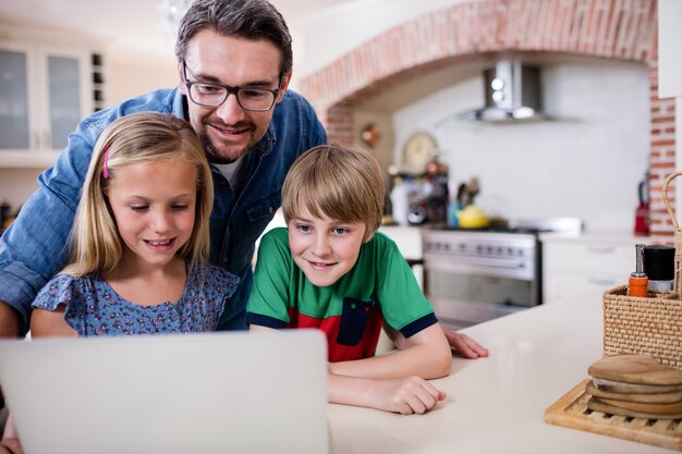 Vader en kinderen die laptop in keuken met behulp van