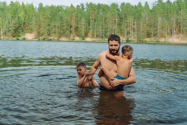 vader en kinderen zwemmen in bosmeer Man leert zoon zwemmen Hoge kwaliteit foto