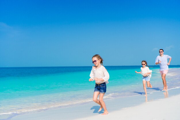 Vader en kleine meisjes lopen op wit zandstrand