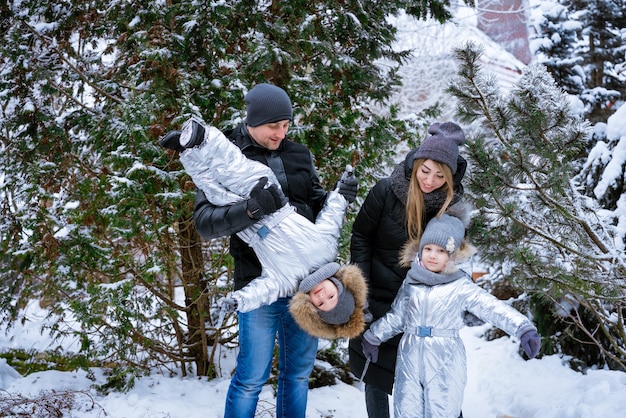 Vader en moeder houden kinderen in hun armen vrolijk lachend familie winterwandeling in bosraisi...