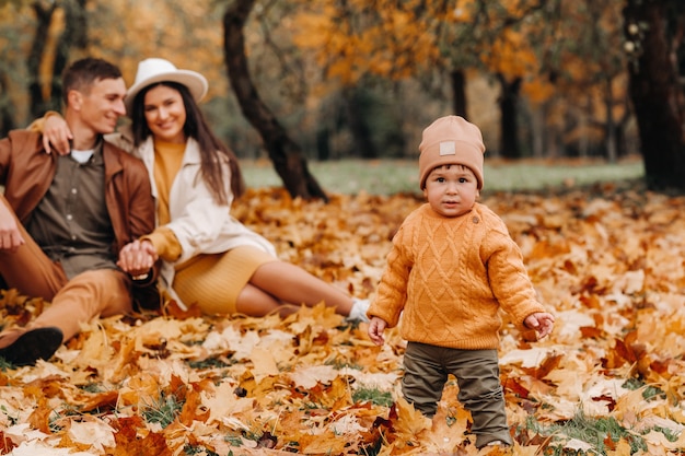 Vader en moeder met zoon wandelen in het herfstpark. Een familie wandelt in de Gouden herfst in een natuurpark.