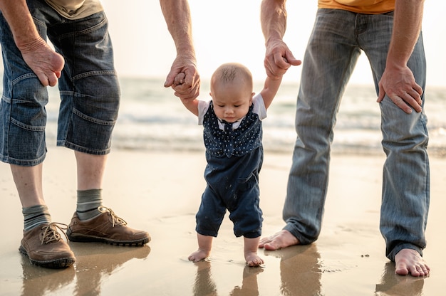 Vader en moeder nemen hun zoon bij de hand voor een strandwandeling in de avondVakantie Familie
