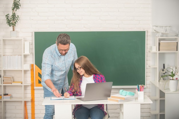 Vader en tienermeisje studeren privéleraar en kind bij computerfamilie helpt vader en dochter