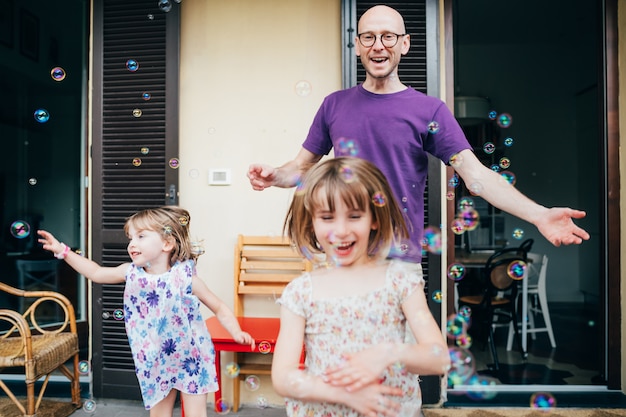 Vader en twee vrouwelijke kinderen buiten spelen zeepbel zeep