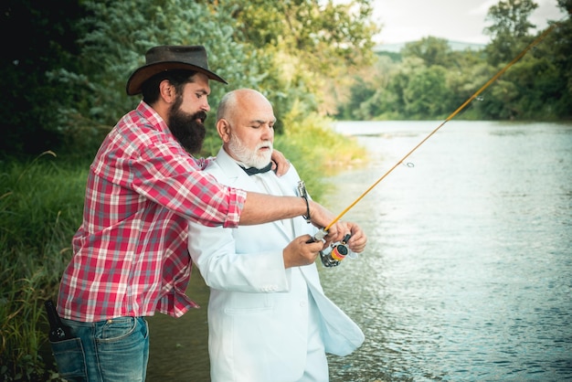 Vader en volwassen zoon visser vissen met een hengel op rivier portret van senior zakenman f