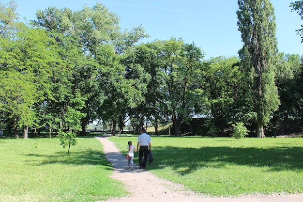 Foto vader en zijn dochter rusten uit in een park met grote groene bomen