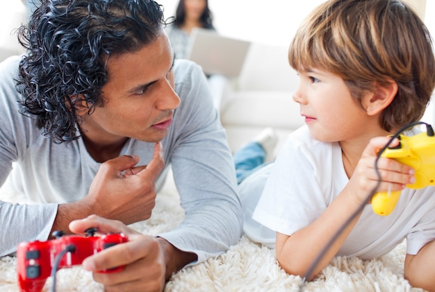 Vader en zijn kleine jongen spelen van videogames op de vloer liggen