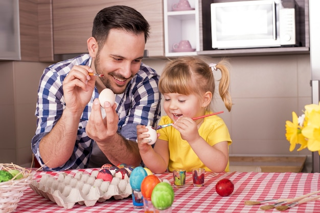 Vader en zijn kleine kind schilderen de paaseieren