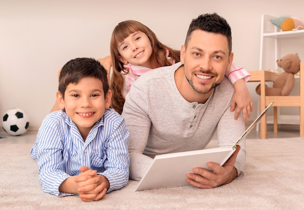 Vader en zijn kleine kinderen die thuis verhaaltje lezen